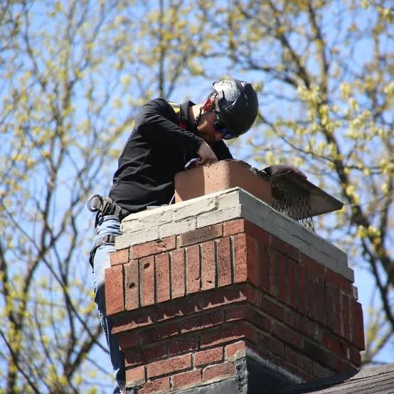 Chimney technician inspecting an open flue at roof level
