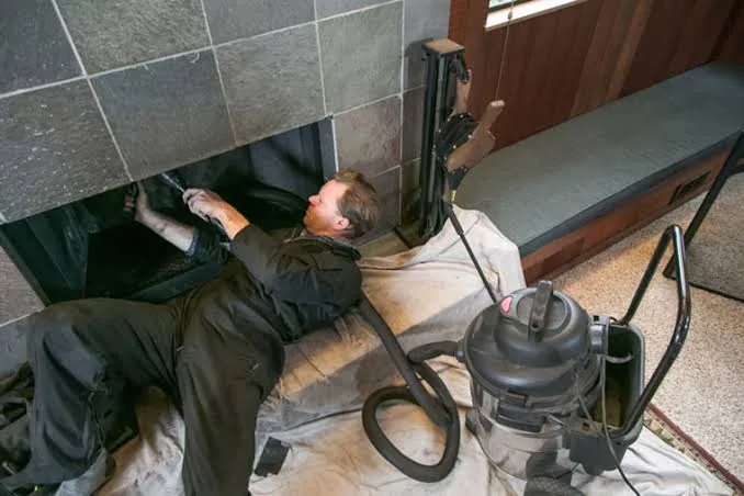 Fireplace opening prepared with protective sheeting and a cleaning vacuum
